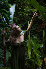 Beautiful woman walking in tropical rain forest, wearing green dress. Woman in jungle. Nature and environment concept. Travel to Asia. Bali, Indonesia