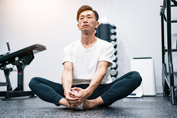 ジムでストレッチ運動をする男性