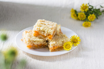 Pieces of apricot orange jam streusel pie on white plate, selective focus