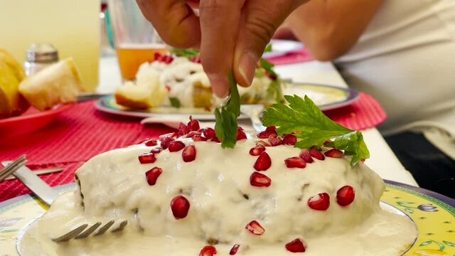 Homemade Mexican Chili with wignut sauce, callled "Chile en Nogada" being decorated with parsley