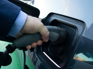 Charging an electric car. Close-up of a power source connected to a charging electrical vehicle.