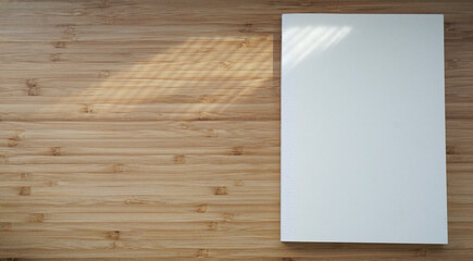 日光の影が反射した木目調のテーブルに置かれた真っ白なノートブック