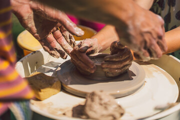 Potter making a clay object on pottery wheel in outdoors. Craftsman moulding clay with hands on pottery wheel