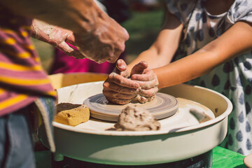 Potter making a clay object on pottery wheel in outdoors. Craftsman moulding clay with hands on pottery wheel
