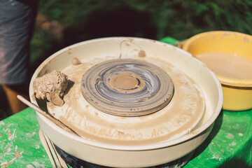 Potter making a clay object on pottery wheel in outdoors. Craftsman moulding clay with hands on pottery wheel