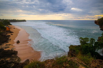 Fototapeta premium Seascape. Spectacular view from Balangan cliff in Bali. Sunset time. Blue hour. Ocean with motion foam waves. Waterscape for background. Nature concept. Soft focus. Slow shutter speed.