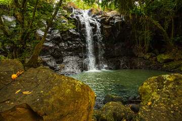 Waterfall landscape. Beautiful hidden waterfall in tropical rainforest. Foreground with big stones. Fast shutter speed. Sing Sing Angin waterfall, Bali, Indonesia