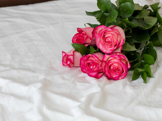 Nice wedding bouquet with five pink and white roses lie on bed in the light room at the morning. Bed pastel composition with flowers. Horizontal, copy space