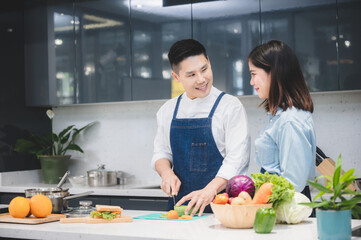 woman and man who young couple cooking food in kitchen at home, people are happy together with love about fresh vegetable lunch meal together, cheerful and smiling to healthy lifestyle