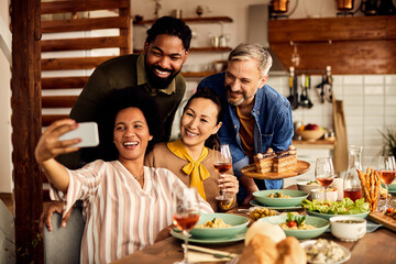 Group of happy multiracial people have fun and take selfie while having lunch at home.