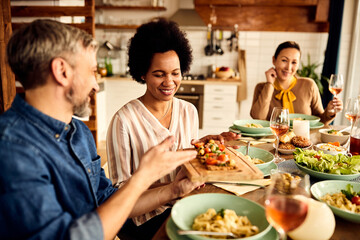Fototapeta na wymiar Smiling African American woman enjoys in lunch with her friends at home.