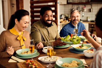 Multi-ethnic group of happy friends enjoy while having lunch together at dining table.