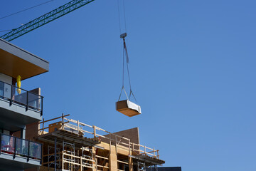 Crane lifting wood for condo building under construction 