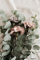beautiful carnation flowers and eucalyptus leaves bouquet  close up on beige linen texture  background.Minimal floral card. Poster