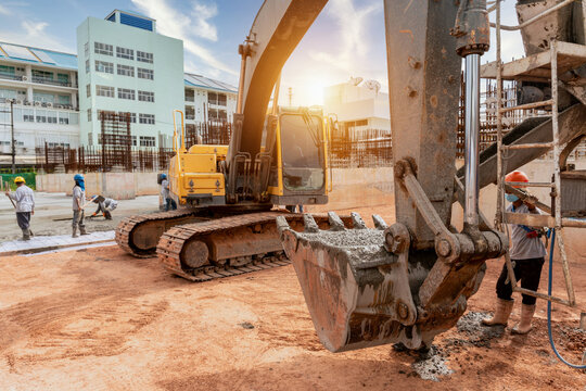 A construction worker with excavator heavy machine and cement truck for pouring a wet concret at building construction site
