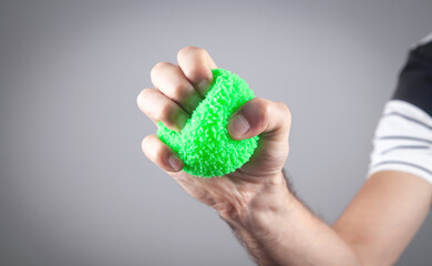 Male hand holding green stress ball.