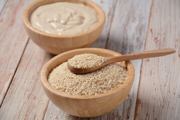 Wooden bowl and spoon with white sesame seeds on vintage wooden background