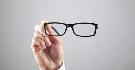 Male hand holding eyeglasses in office.