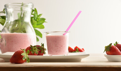 Glass and jug full of strawberry smoothie isolated background