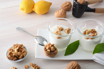 Yogurt with walnuts on white wooden table elevated view