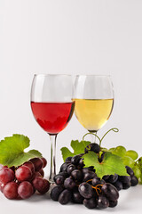 Wine composition with wine glasses and grape. Glasses of red and white wine and variety of grape on white background.