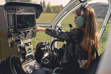 Fototapeta na wymiar Preteen girl in headset pointing at dashboard in helicopter cockpit