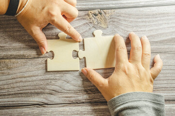 A group of business people assembling jigsaw puzzle.Business woman hands connecting jigsaw puzzle. Business solutions, success and strategy concept. Close up photo with selective focus.