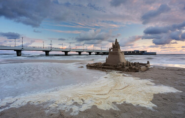 Zamek z piasku na plaży w Kołobrzegu, w pięknych barwach wschodzącego słońca. - obrazy, fototapety, plakaty