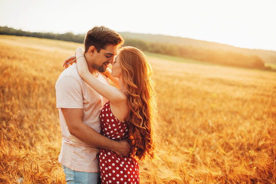 Back view photo of a loving couple embracing and having intimate moments in a field during a perfect sunset