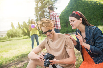 Guy showing enthusiastic girl photos in nature