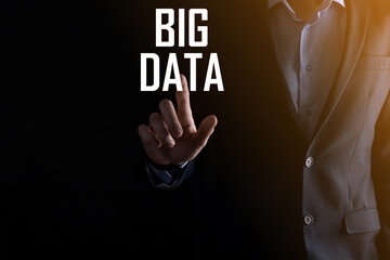 Businessman in a suit on a dark background holds the inscription BIG DATA. Storage Network Online Server Concept.Social network or business analytics representation