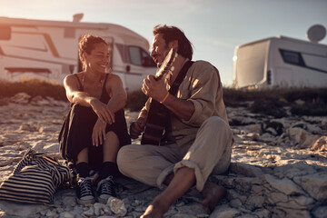 Man singing to his girlfriend on a beach.
