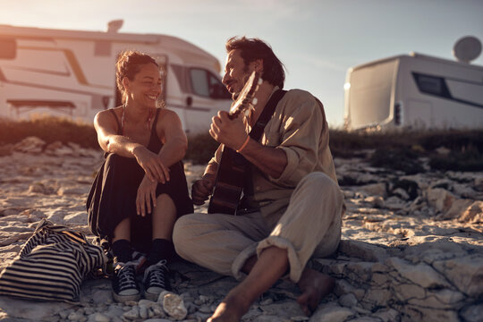 Man singing to his girlfriend on a beach.