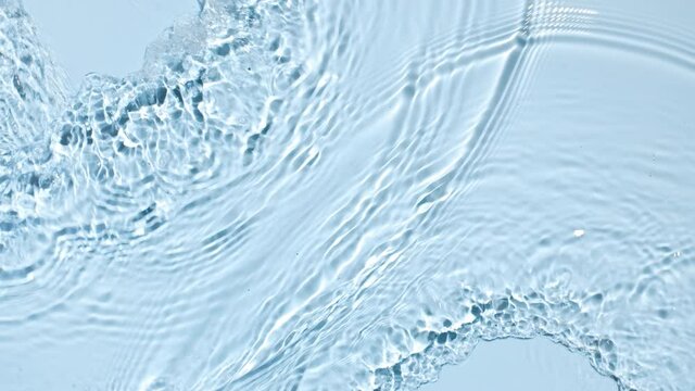 Water flows from opposite sides creating waves and ripples on light blue background | Background shot for skincare products commercial