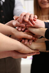 Group of people in suits crossed hands in pile for win