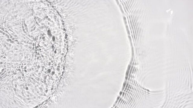 Water ripples with the equal frequency creating concentric circles on light grey background | Background shot for skincare products commercial