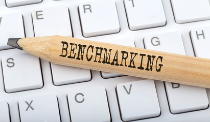 Text BENCHMARKING on wooden pencil on white keyboard. Business concept