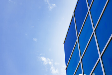 Fototapeta na wymiar Glass skyscraper building with cloudy blue sky background