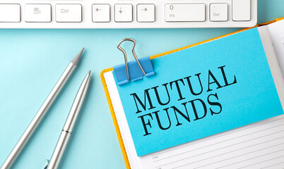 MUTUAL FUNDS text on sticker on the blue background with pen and keyboard