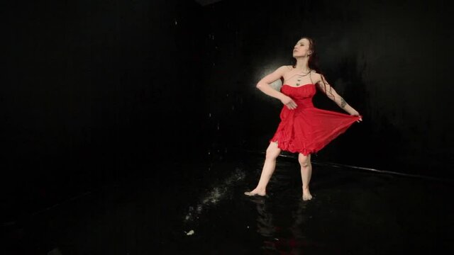 Woman in a red dress is showing a show, she is dancing in the water.