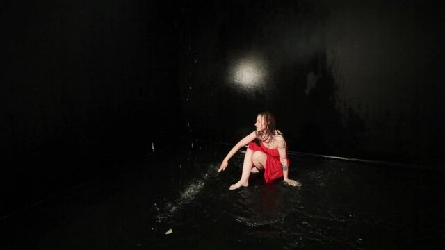 Woman in a red dress is showing a show, she is dancing in the water.