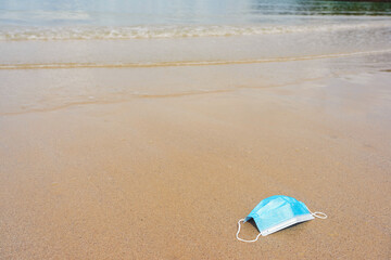 Fototapeta na wymiar Blue face mask on sand beach with waves and sea