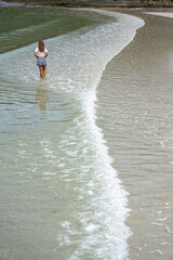 Asian woman walking on beach with curves of white waves