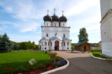 Fototapeta na wymiar Kirov, Russia - August 26, 2020: The white walls of the Trifonov Monastery. Christian Orthodox Church on the background of a blue sky with clouds