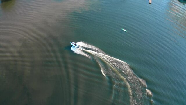 Blue boat on the river at sunset. People sailing in boats among beautiful landscape in the evening. Rest in summer. Aerial view