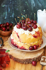 Cherry cake. Yeast bun with cherries and cream. Top view, wooden and blue background.