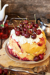 Cherry cake. Yeast bun with cherries and cream. Top view, wooden background.
