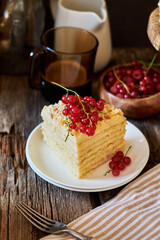 Cake on a wooden cake stand. Shortcrust pastry cake, decorated with red currants. Wooden background, side view.
