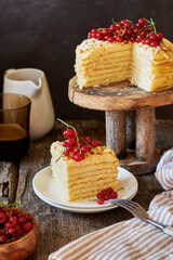 Cake on a wooden cake stand. Shortcrust pastry cake, decorated with red currants. Wooden background, side view.