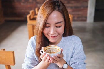 Portrait image of a young asian woman smelling and drinking hot coffee